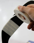 Hand holding a roll of white tape against a blurred background