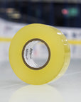 Roll of yellow tape on a reflective surface with a blurred background