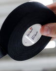 Person holding a roll of black tape with a visible brand label.