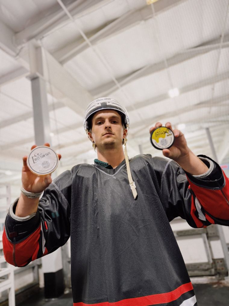 Player in a helmet holding up Best Dam Tape and Best Dam Wax