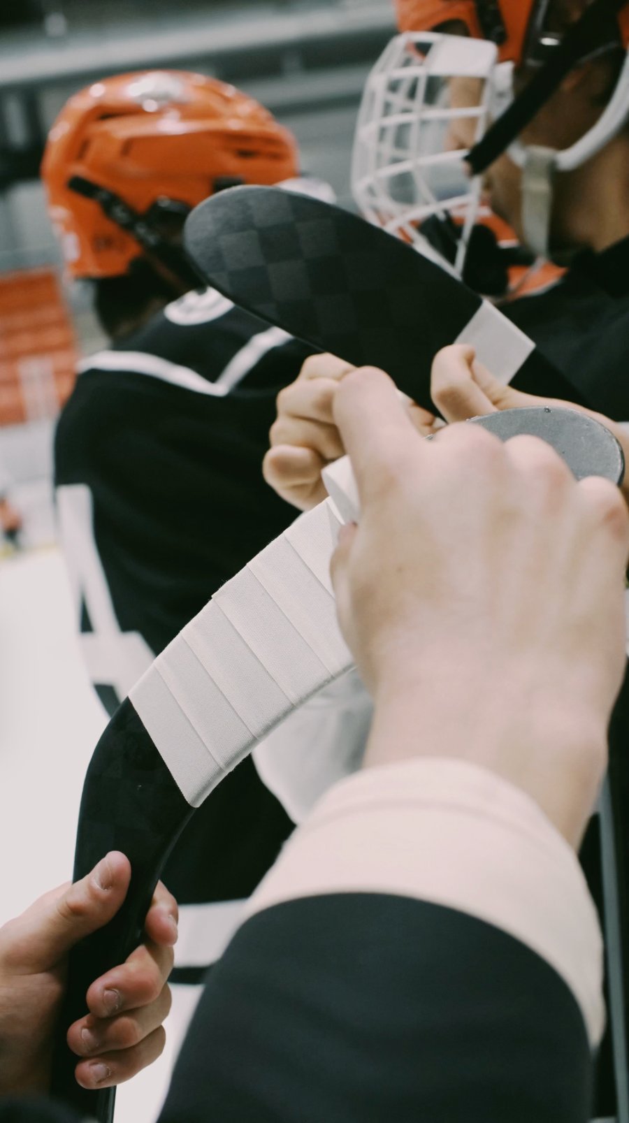 Junior players in helmets taping their stick blades with Best Dam white cloth tape