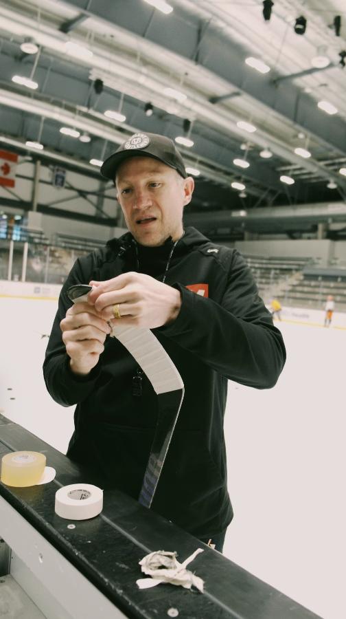 Coach wrapping a stick blade with Best Dam cloth tape at the rink
